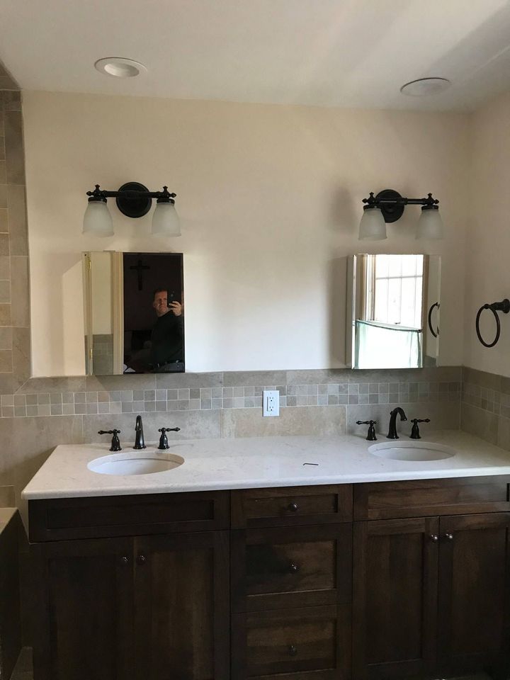 Bathroom with double sinks, dark wood vanity, wall-mounted mirrors, and matching light fixtures above each sink.